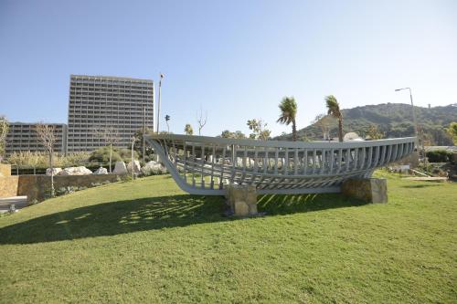 a bench in a field with a city in the background at Rodos Palace Hotel in Ixia