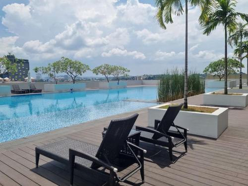 a couple of chairs sitting next to a swimming pool at HarbourBay Residence. Batam. Studio. 1min to Ferry in Jodoh