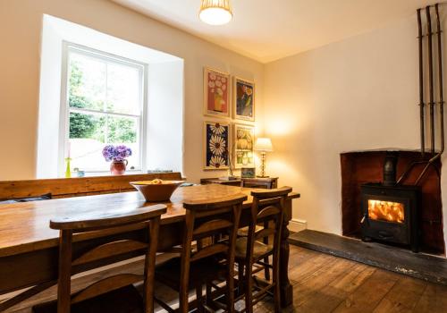 a dining room with a table and a wood stove at Panteg - a gorgeous retreat near the coast for 10 in Cardigan