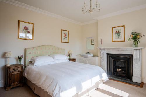 a bedroom with a white bed and a fireplace at Little Oak in Holbeton