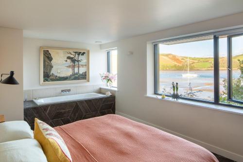 a bedroom with a bath tub and a large window at Horsepool Boathouse in Salcombe