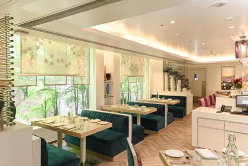 a restaurant with tables and chairs and windows at The Ashtan Sarovar Portico in New Delhi