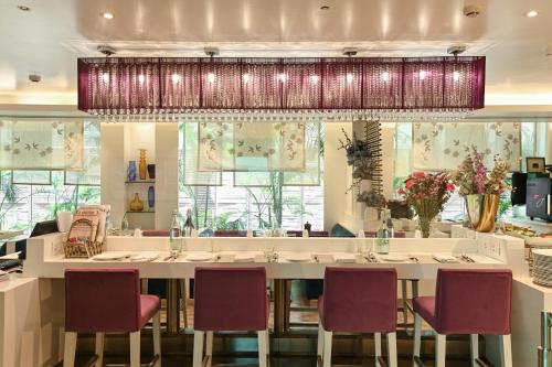 a restaurant with a large white counter with chairs at The Ashtan Sarovar Portico in New Delhi