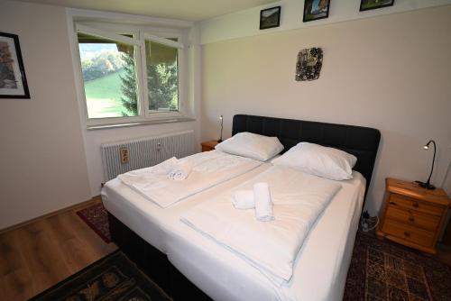 Schlafzimmer mit einem Bett mit weißer Bettwäsche und einem Fenster in der Unterkunft top 39 haus 1 in Kaprun