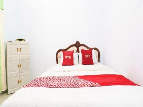 un letto con due cuscini rossi sopra di OYO 93249 Wisma Jasmine Syariah a Kuningan