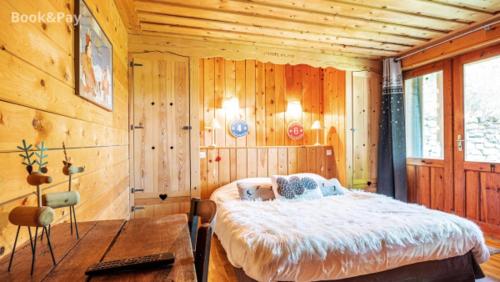 1 dormitorio con 1 cama y pared de madera en Chalet Pomme de Pin, en Formiguères