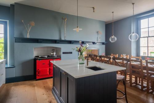 a kitchen with blue walls and a red cabinet at Hummingbird House in Holbeton