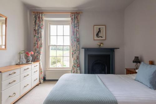 a bedroom with a bed and a fireplace and a window at Hummingbird House in Holbeton