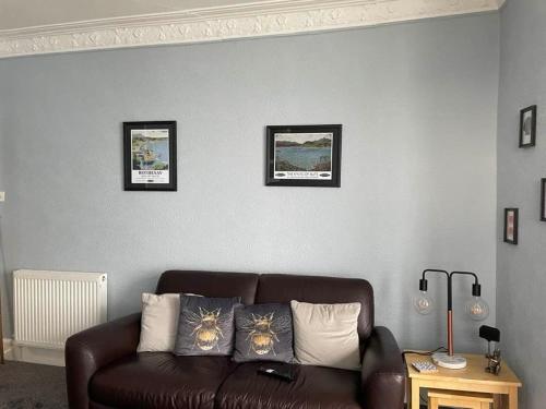 a living room with a brown leather couch and three pictures at Bellevue Bute, Luxury 2 bedroom sea view flat in Rothesay