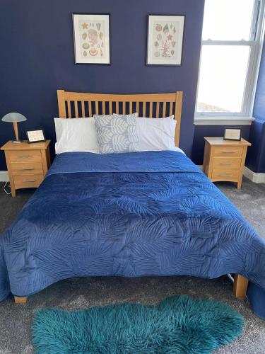 a blue bed with a blue comforter and two windows at Bellevue Bute, Luxury 2 bedroom sea view flat in Rothesay