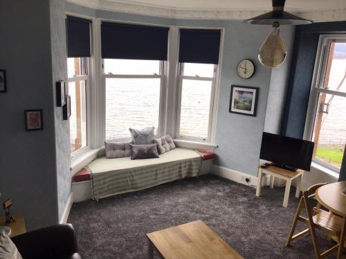 a living room with a bed and two windows at Bellevue Bute, Luxury 2 bedroom sea view flat in Rothesay