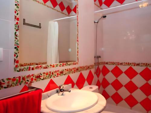 baño rojo y blanco con lavabo y espejo en Apartamento cerca de la playa los Bateles, en Conil de la Frontera