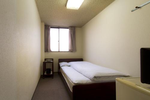 a small room with a bed and a window at Hotel Wako in Osaka