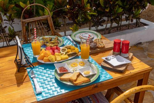 a table topped with plates of breakfast foods and orange juice at Cactus lodge Zanzibar in Nungwi
