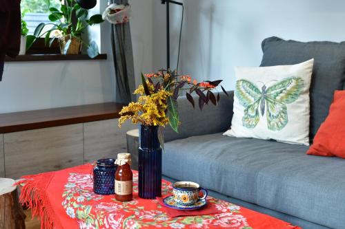a table with a vase with a butterfly pillow on a couch at Gościniec Skorusa in Kościelisko