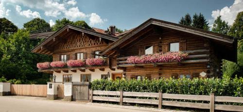 a wooden house with flowers on the side of it at Ferienwohnungen Gerold, Kreuth-Reitrain in Oberach