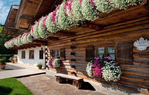 a wooden house with flowers on the side of it at Ferienwohnungen Gerold, Kreuth-Reitrain in Oberach