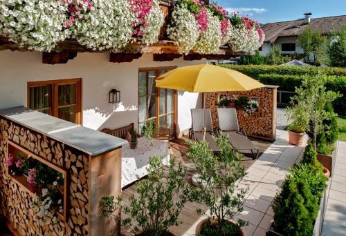 an outdoor patio with flowers and an umbrella at Ferienwohnungen Gerold, Kreuth-Reitrain in Oberach
