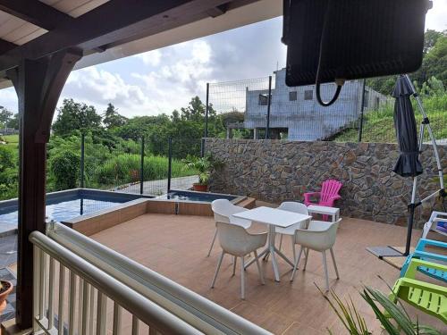 une terrasse avec une table, des chaises et une piscine dans l'établissement Bas de Villa FloriRose, à Rivière-Salée