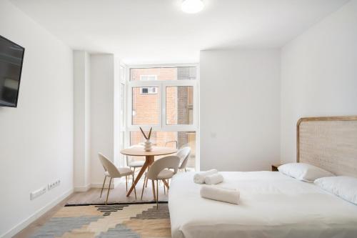 een slaapkamer met een bed en een tafel en stoelen bij apartamentos en vallecas in Madrid