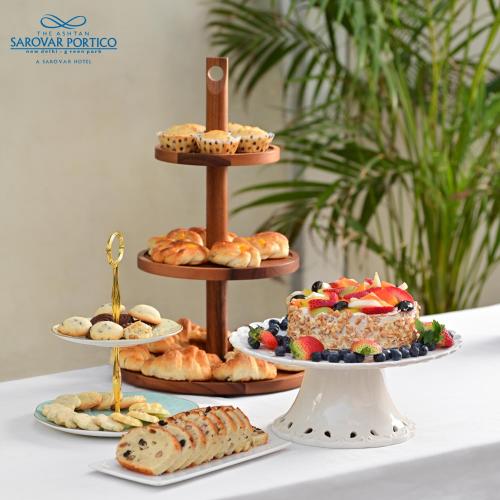 a table topped with plates of pastries and cakes at The Ashtan Sarovar Portico in New Delhi