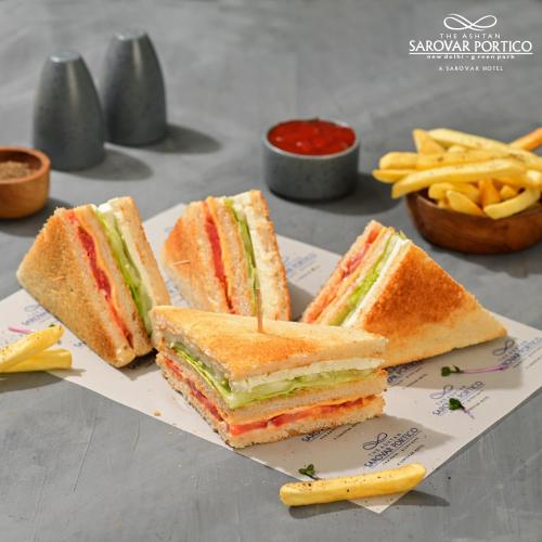 a sandwich cut in half on a plate with french fries at The Ashtan Sarovar Portico in New Delhi