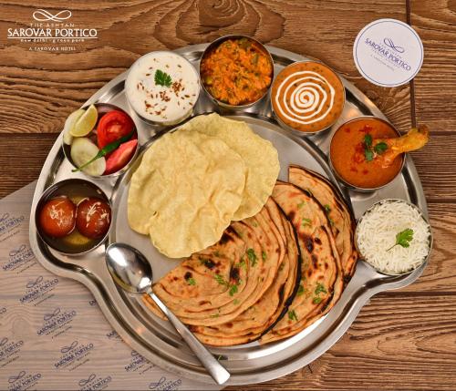 a tray of indian food on a wooden table at The Ashtan Sarovar Portico in New Delhi