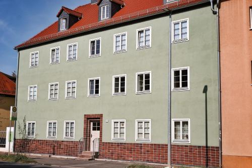 un gran edificio blanco con techo rojo en Pößnecker Werkstätten -Tessenow Wohnung en Pößneck
