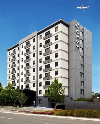 a large white building with an airplane flying over it at Quest Mascot in Sydney