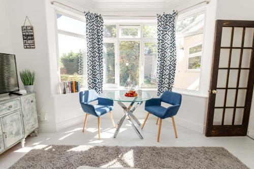 a dining room with a glass table and two blue chairs at Queens Park Views by Grandeur Property in Bournemouth
