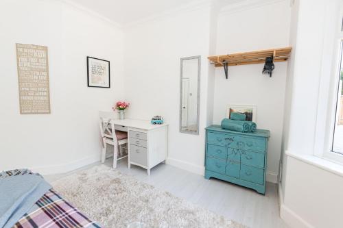 a bedroom with a desk and a bed with a blue cabinet at Modern flat, sleeps 4, close to beach,Parking,WiFi - Queens Park Views in Bournemouth