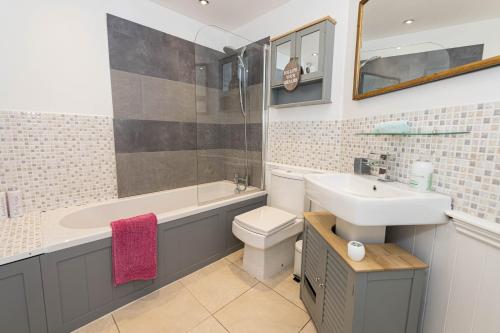 uma casa de banho com um lavatório, uma banheira e um WC. em Modern flat, sleeps 4, close to beach,Parking,WiFi - Queens Park Views em Bournemouth