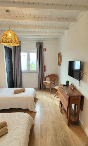 a bedroom with two beds and a tv and a table at Cantinho de Milfontes 1 Twin in Vila Nova de Milfontes