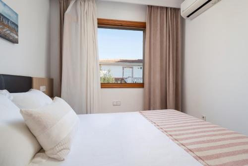 a bedroom with a white bed and a window at Villa Isabel in Playa de Muro
