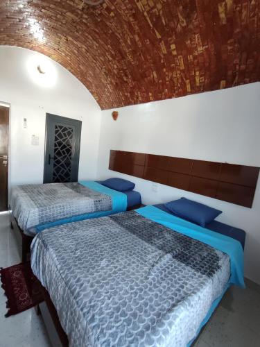 Jamaica Guest House في أسوان: سريرين في غرفة نوم مع جدار من الطوب