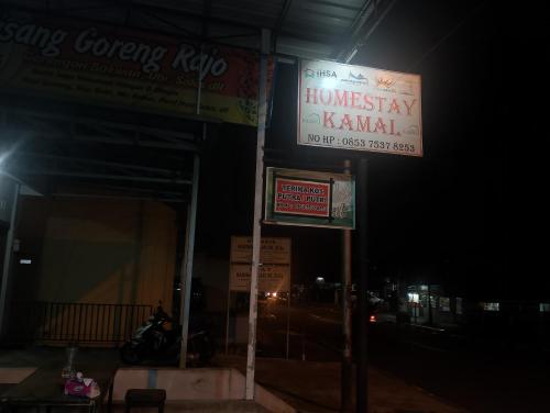 un panneau devant un bâtiment la nuit dans l'établissement Homestay Kamal, à Padangpanjang
