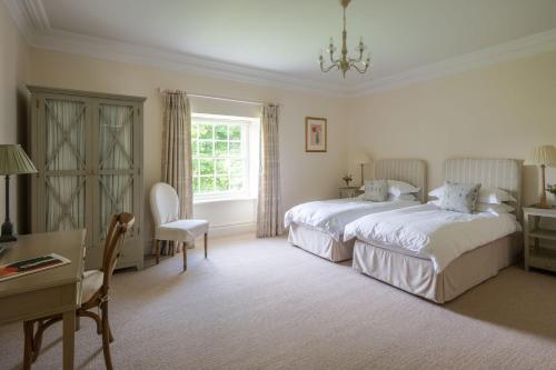 een slaapkamer met 2 bedden, een tafel en een bureau bij Mulberry House in Holbeton