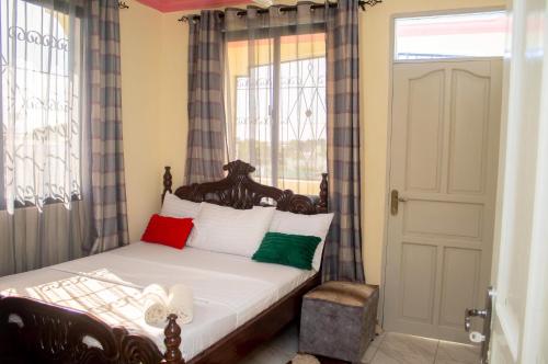 a bedroom with a bed with colorful pillows and a window at At's Apartment in Mombasa