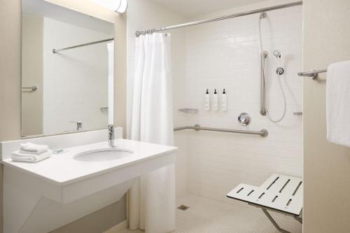 a white bathroom with a sink and a shower at SpringHill Suites St. Louis Airport/Earth City in Bridgeton