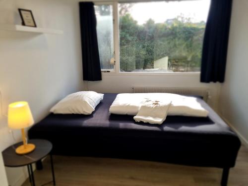 ein Bett mit zwei Kissen und ein Fenster in einem Zimmer in der Unterkunft Slottets Anneks in Rønne