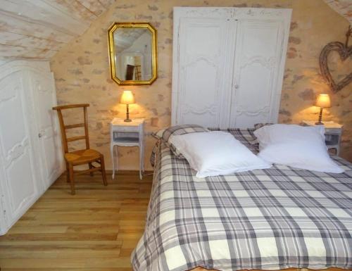 una camera da letto con un letto, uno specchio e una sedia di Le Clos des Lavandes a Ruffey-lès-Beaune