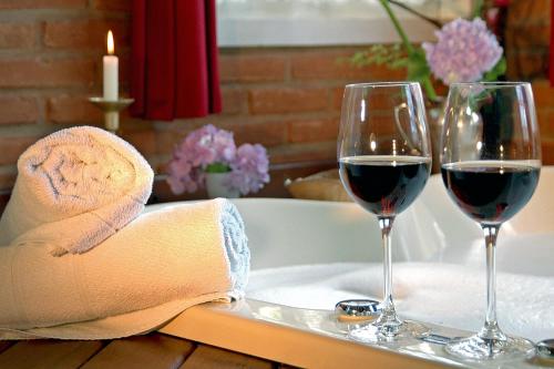 two glasses of wine on a tray in a bath tub at Pousada Olho D'Água in Visconde De Maua