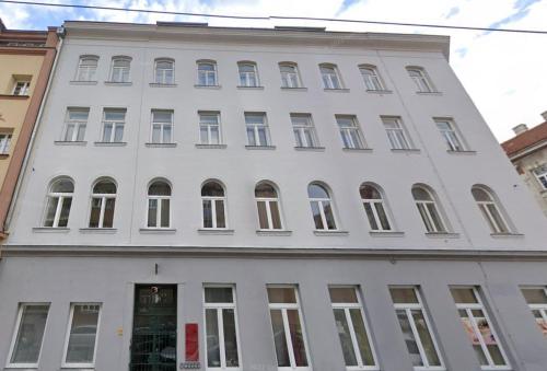 ein weißes Gebäude mit vielen Fenstern auf einer Straße in der Unterkunft Appartement Cervantes 13 in Wien
