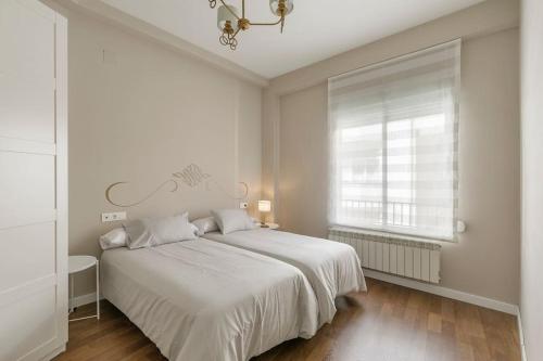 a white bedroom with a bed and a window at Sara Love Downtown in Granada