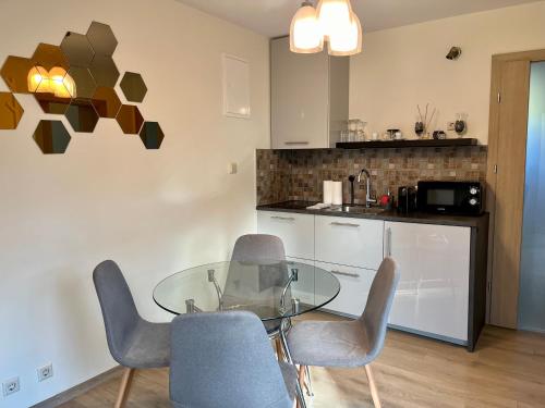 uma cozinha com uma mesa de vidro e cadeiras num quarto em Eden House em Druskininkai