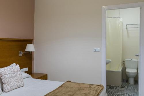 ein Schlafzimmer mit einem Bett und ein Badezimmer mit einem WC in der Unterkunft Hostal Imperial in Merida