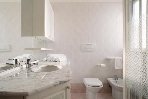 ein weißes Bad mit einem Waschbecken und einem WC in der Unterkunft Appartamento al Sole in Colà di Lazise