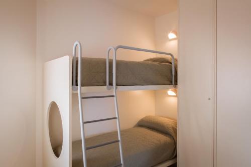Zimmer mit Etagenbett, 2 Etagenbetten und einem Spiegel in der Unterkunft Appartamento al Sole in Colà di Lazise