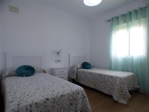 1 Schlafzimmer mit 2 Betten mit blauen Kissen und einem Fenster in der Unterkunft Casa rural Majadales piscina privada alta calidad in Conil de la Frontera