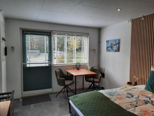 een slaapkamer met een tafel, een bed en een raam bij B&B Vogelhof in Wapenveld